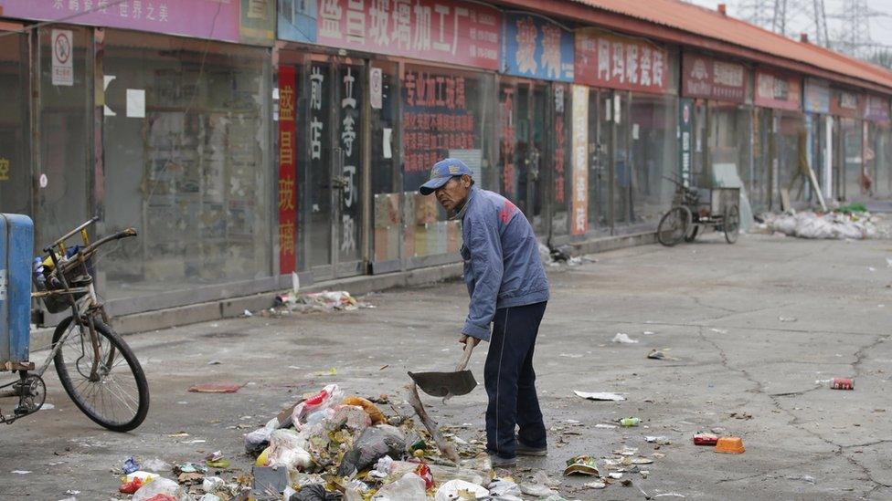 A man clears rubbish at a closed market in Beijing