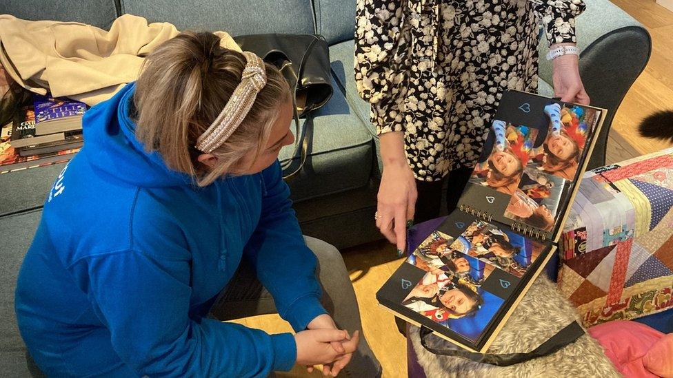 Emily Wadds showing Rebecca Thomas, from Soundabout, a photo album from lockdown one