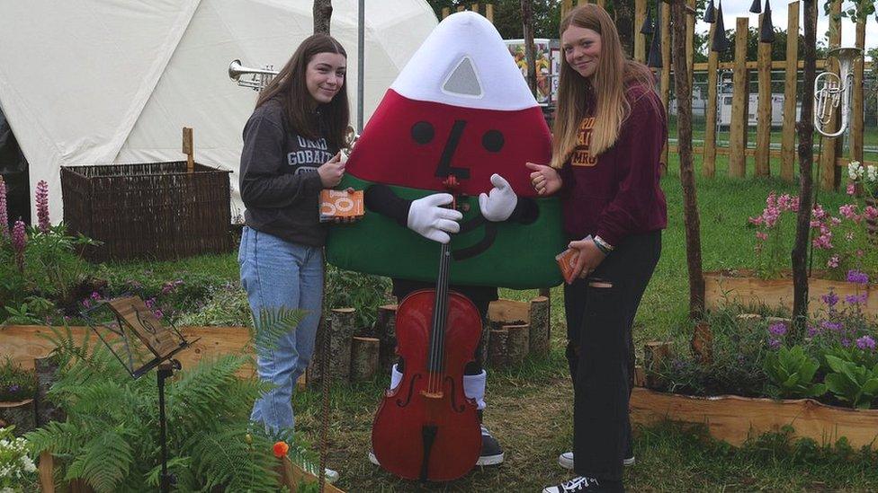 Eos a Leia, disgyblion Ysgol Brynhyfryd fu'n tywys Mistar Urdd o amgylch y maes heddiw, gan alw heibio'r Arddorfa am wers sielo