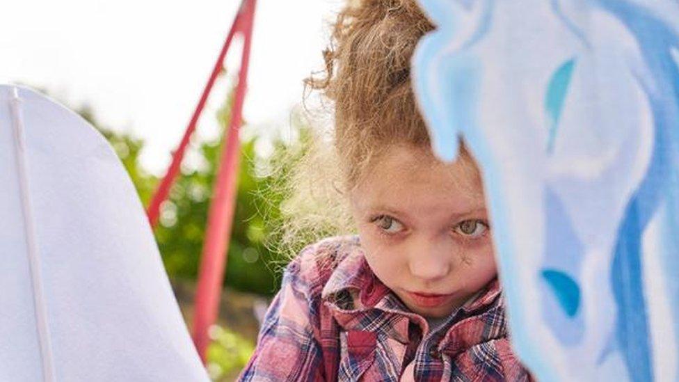 Chid looking out from behind some play equipment