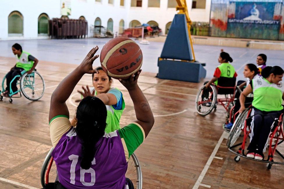 A player tries to block another who is aiming for the hoop