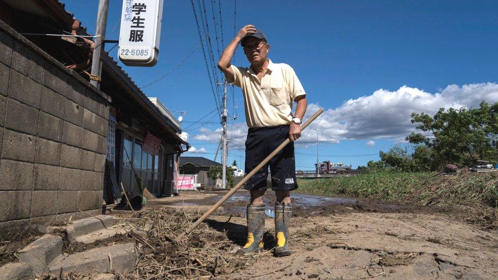 A man clears mud from his store following the passage of Typhoon Hagibis