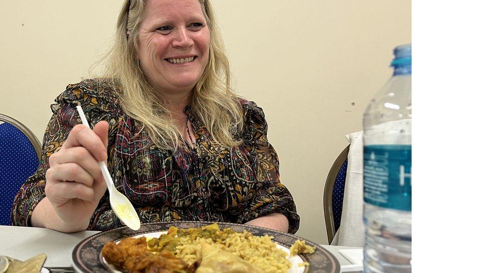 A woman eats curry at a table