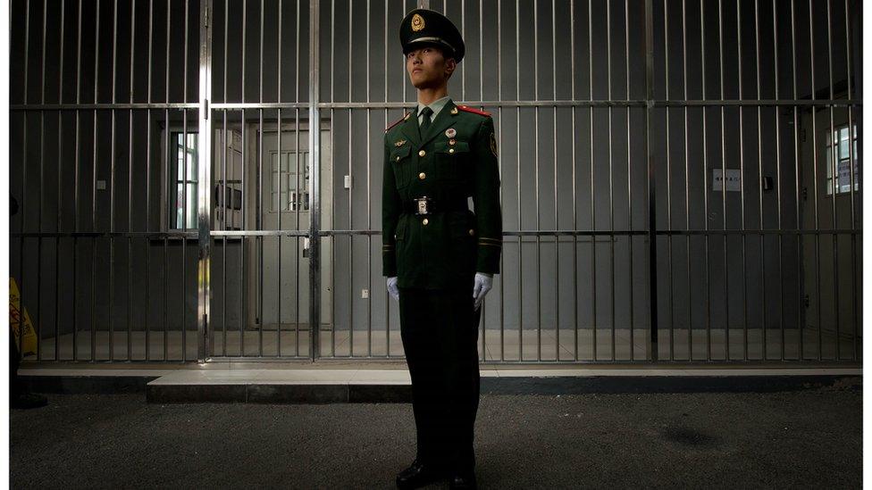 A paramilitary guard stands before the bars of a main gate to the No.1 Detention Center during a government guided tour in Beijing in October 2012