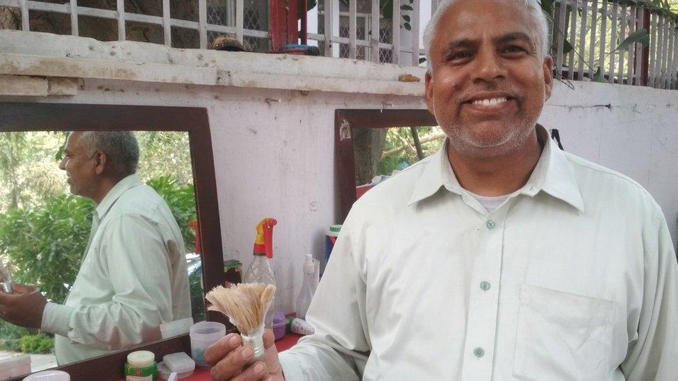 Balwant Singh poses in front of his street shave shop.