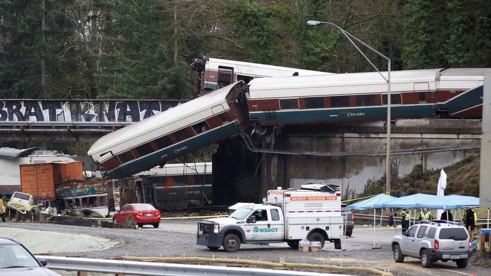 three train carriages coming off a bridge on to a road