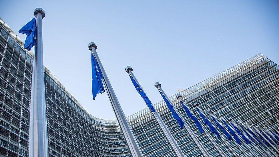 A view of European flags in front of the European Commission headquarters at the Berlaymont Building in Brussels