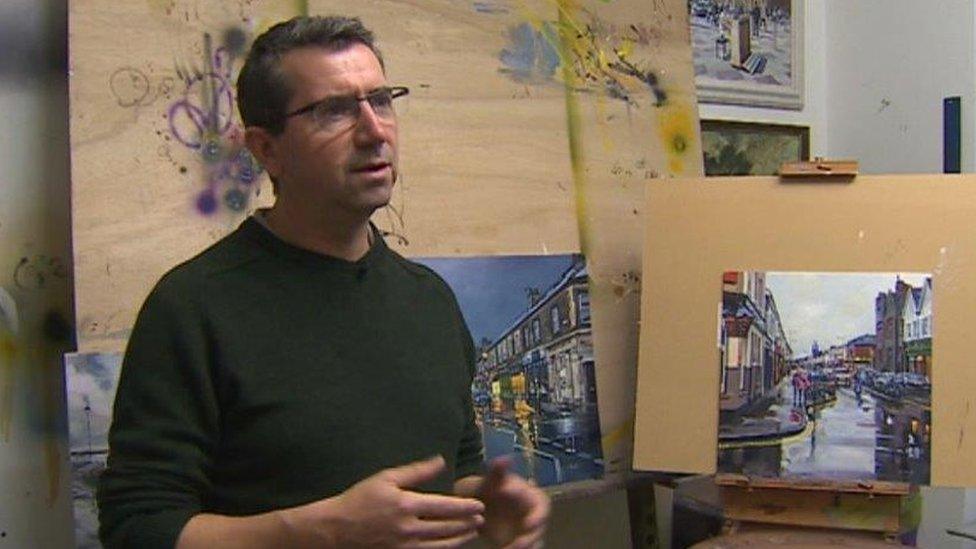 Malcolm P Murphy in front of his oil paintings