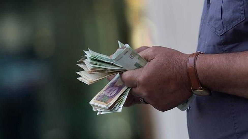 Photo of man holding Iranian currency