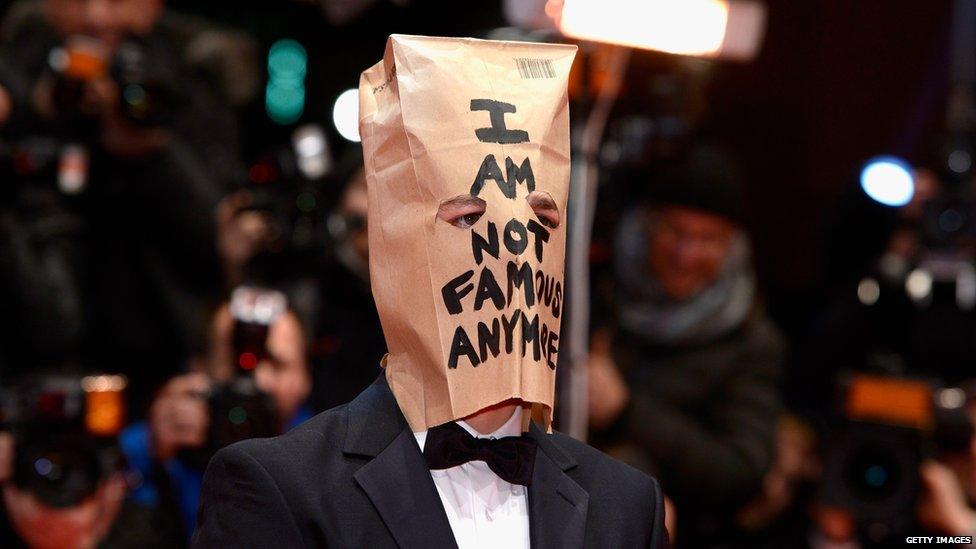 Shia LaBeouf wearing a paper bag on which the words 'I am not famous anymore' are written