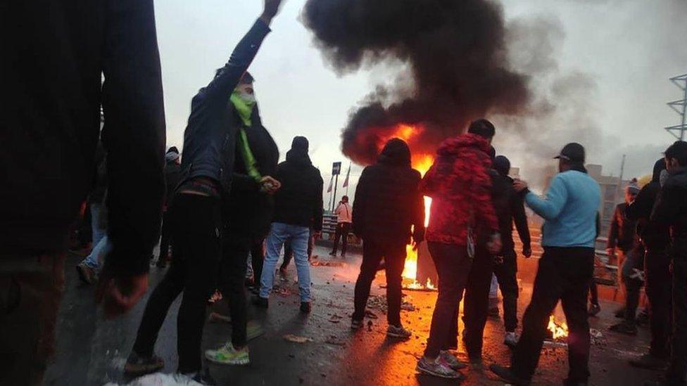 Iranian protesters gather around a fire during a demonstration against an increase in petrol prices in Tehran (16 November 2019)