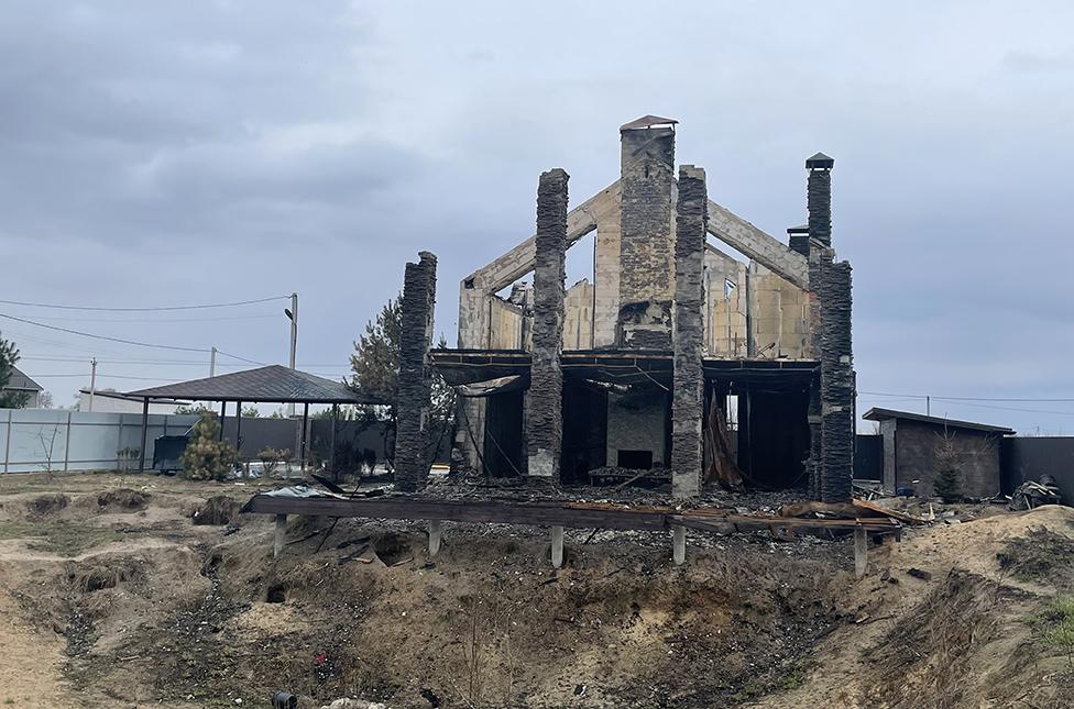 The family's burned out house, east of Kyiv - their dogs, also killed, are lying in the garden (not pictured)