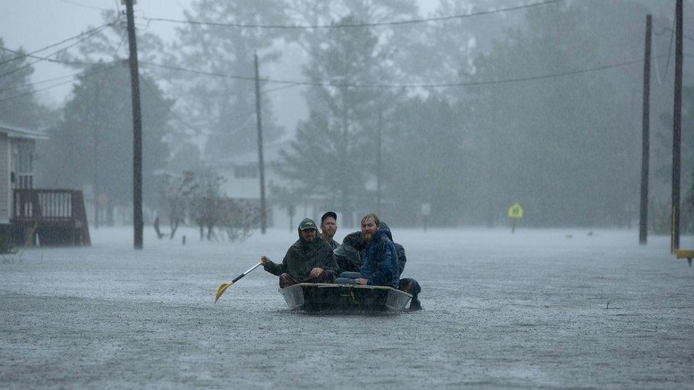 Volunteers in a small boat in flooded conditions