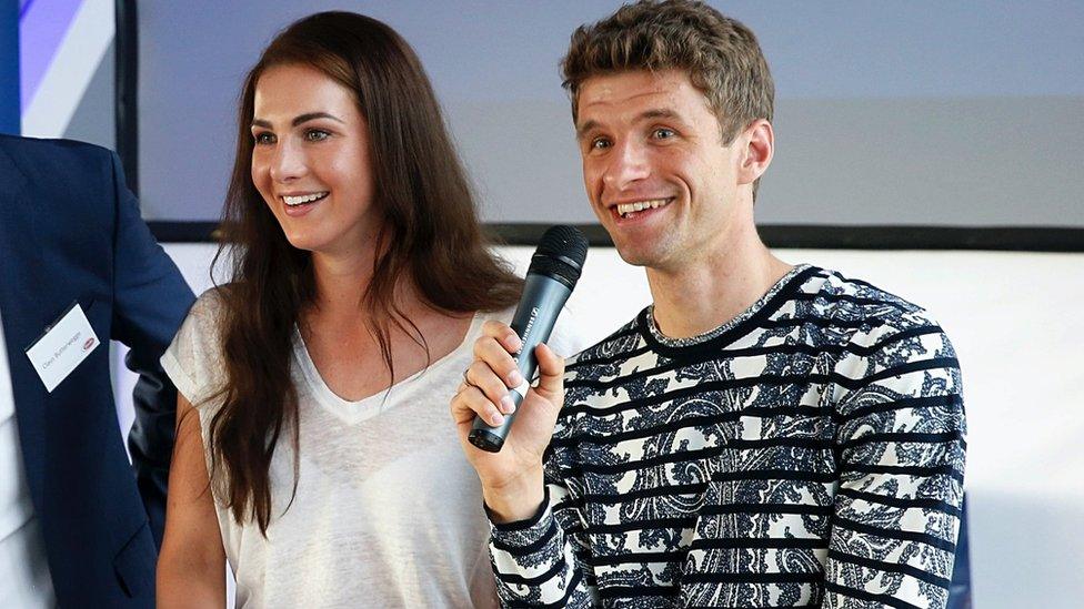 Thomas Muller holding a microphone standing next to a woman