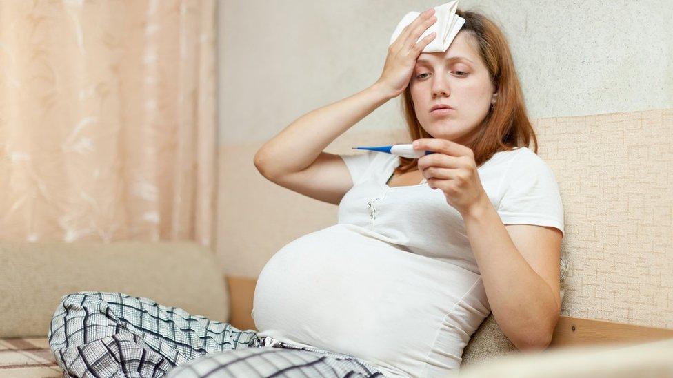 A pregnant woman with a thermometer