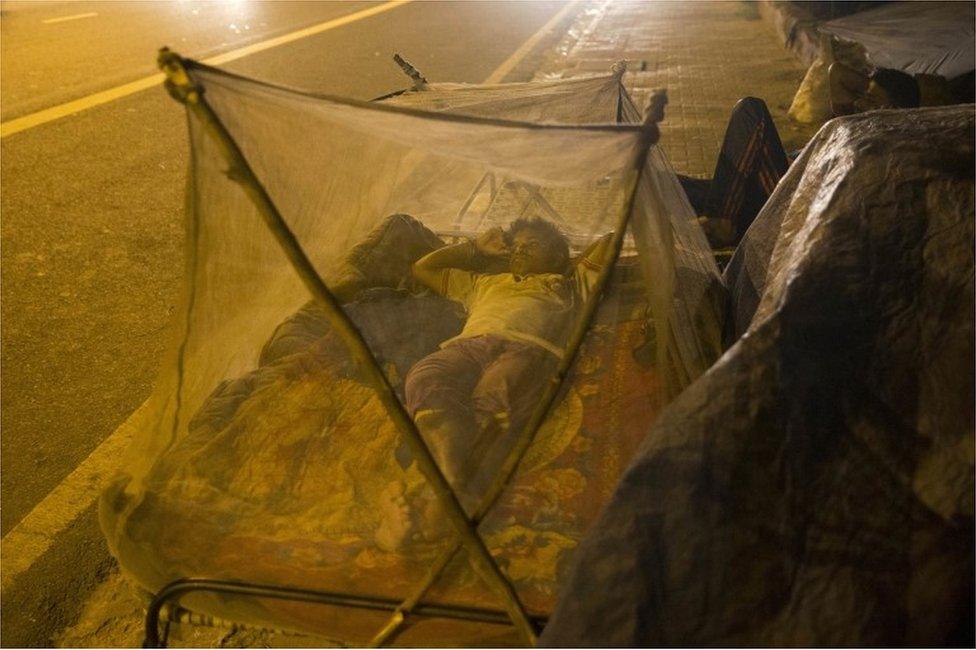 An Indian migrant labourer sleeps near a roadside under mosquitoes nets in New Delhi, India, Wednesday, Sept. 14, 2016