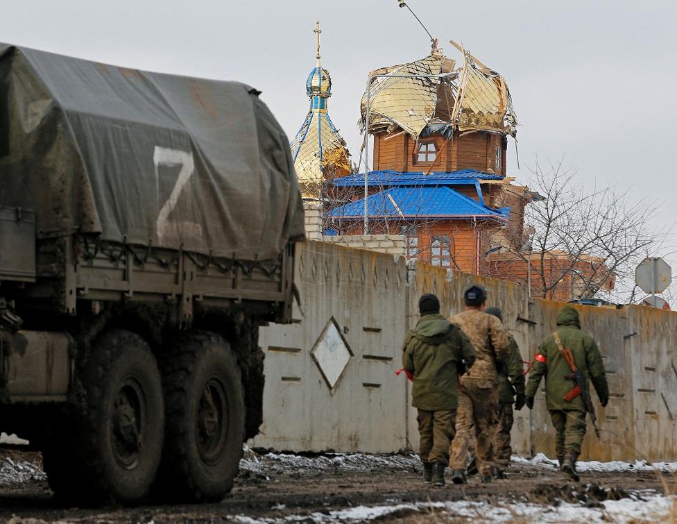 Troops walk past damaged church