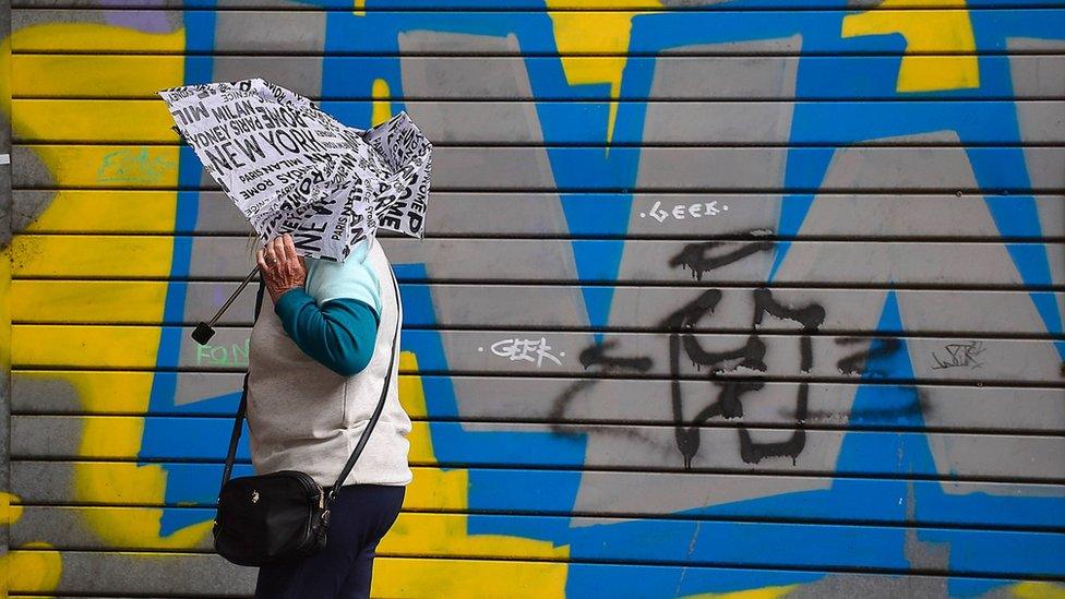 Woman with umbrella walking past graffiti