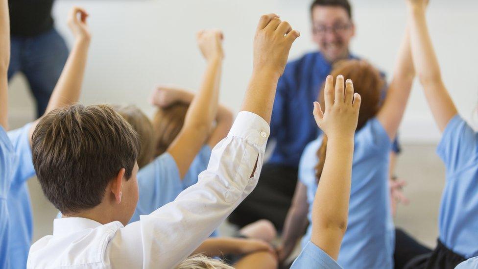 Students holding arms up in classroom