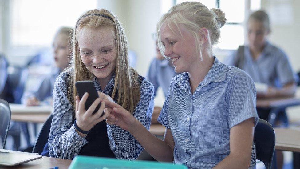 Two girls on phones in class