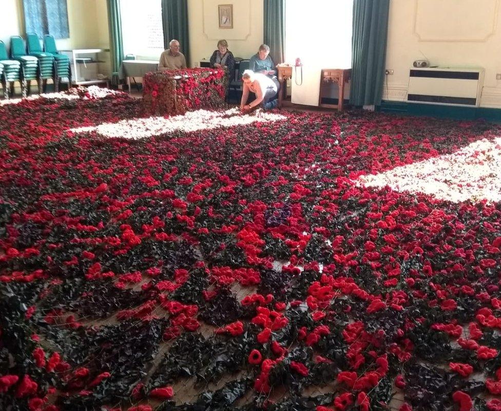 Volunteers attaching the poppies to the netting