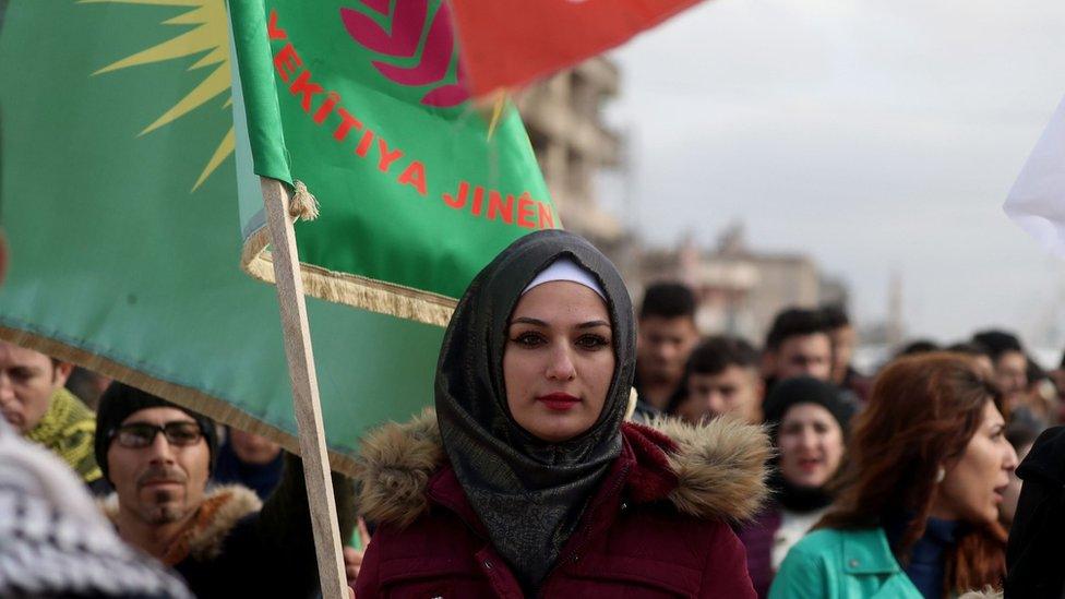 Syrian Kurdish protesters wave flags during a demonstration in the north-eastern Syrian Kurdish-majority city of Qamishli on December 28, 2018, against threats from Turkey to carry out a fresh offensive following the US decision to withdraw their troops