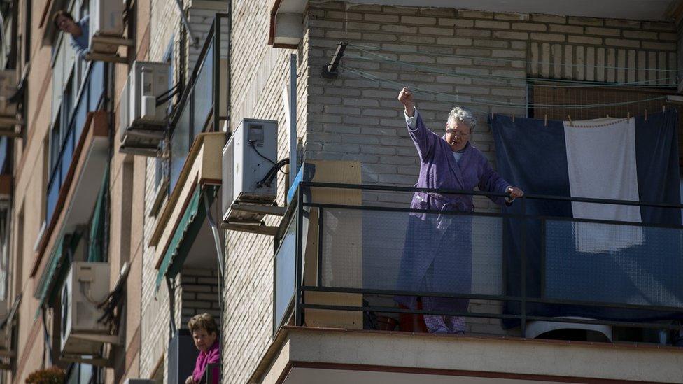 A woman reacts from a balcony to a protest during the International Women's Day on March 08