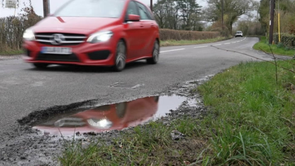 Car driving by a pothole