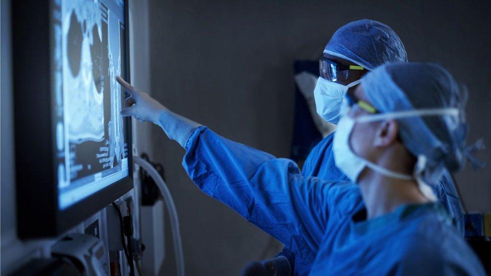 Two surgeons analysing a patient's medical scans during surgery