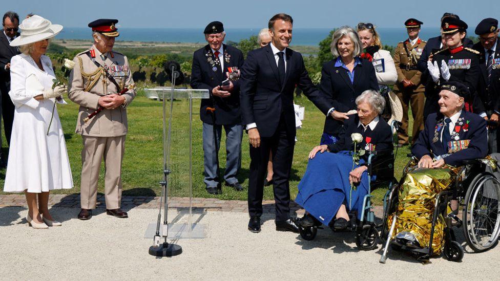 France's President Emmanuel Macron (C) reacts after awarding 104-years-old British World War II veteran, Christian Lamb (2ndR), who helped to plan the D-Day landings in Normandy, with the insignia of Knight in the Legion of Honour order, as Britain's Queen Camilla (L) and Britain's King Charles III (2ndL) look on