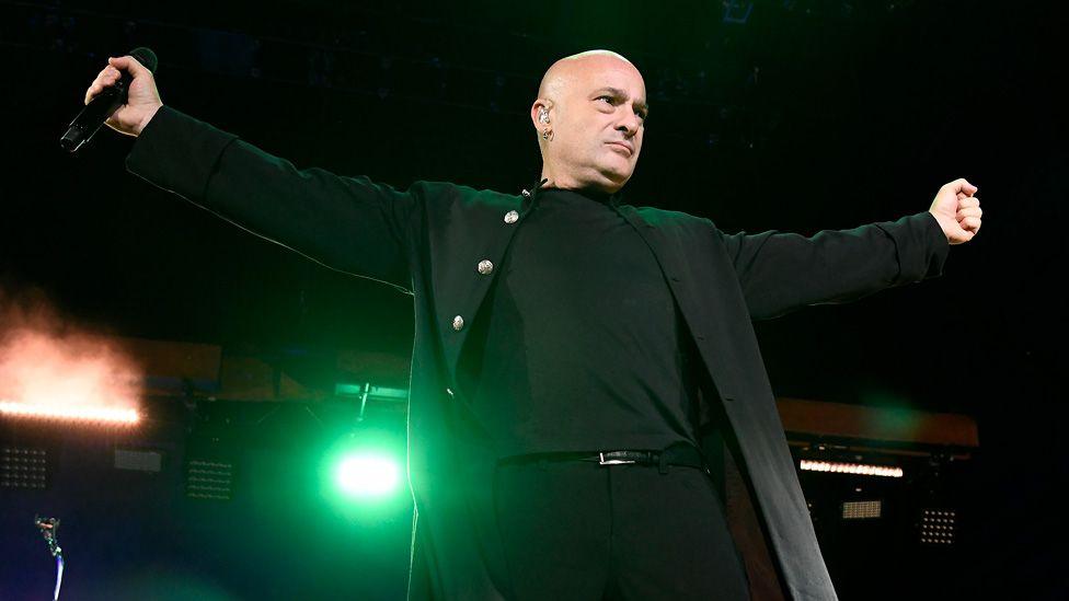 David Draiman of Disturbed with his arms outstretched on stage