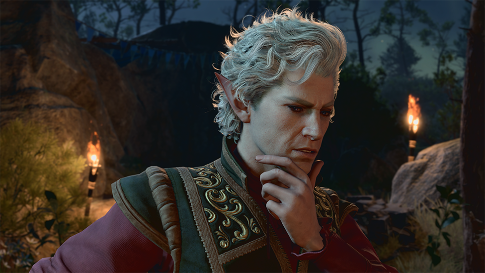 Screenshot shows a male character dressed in an elaborately embroidered jacket holding his chin in his hand. He looks thoughtful, but also as if he could be scheming or plotting. He appears to be in a woodland clearing lit by two flaming torches.