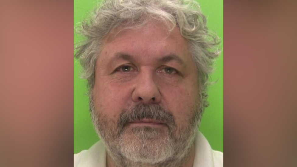 Custody photo of Lee Whalley with wavy grey hair, a grey beard and a light-coloured polo shirt