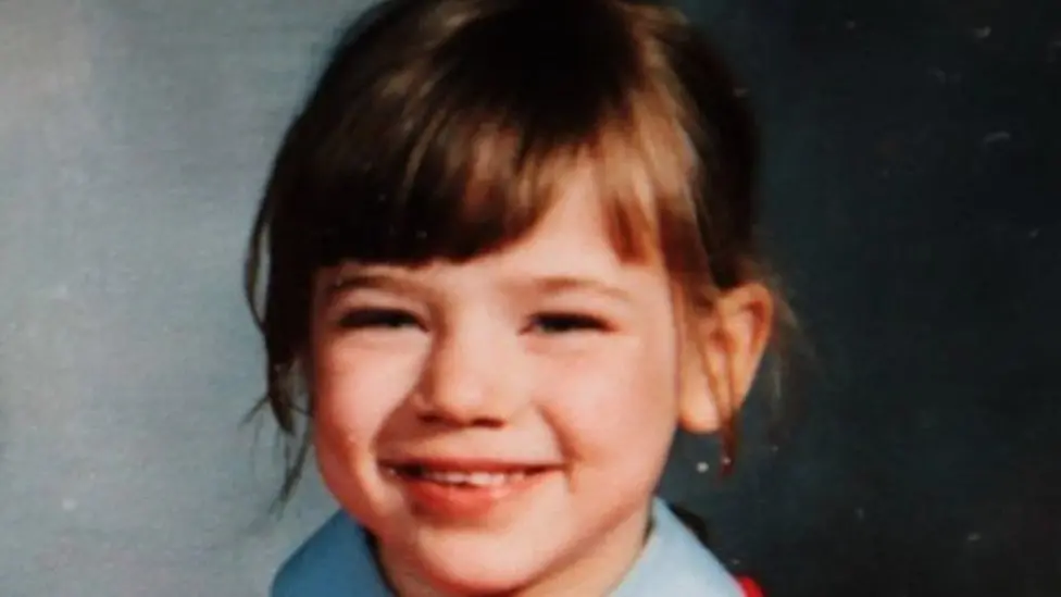 Nikki Allan smiling at the camera. She has brown hair. 