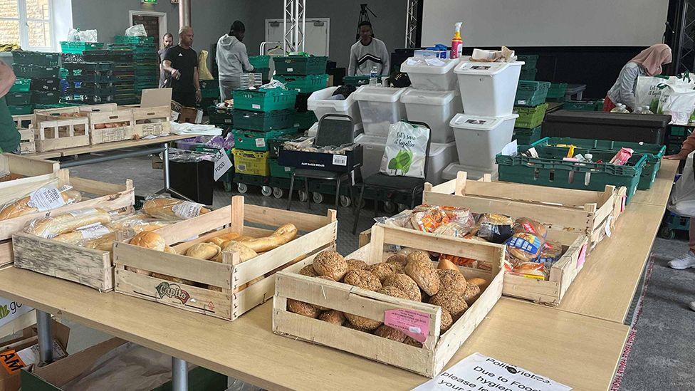 Workers at the Trussell Trust food bank in Bradford help sort out food with loaves of bread in wooden trays in the foreground