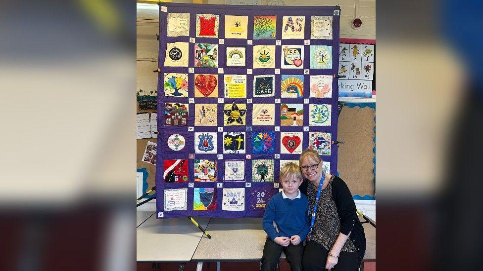 Paula Martin sat with a pupil in front of a quilted piece of art