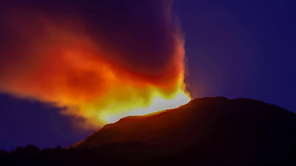 Orange and yellow flames light a night's sky