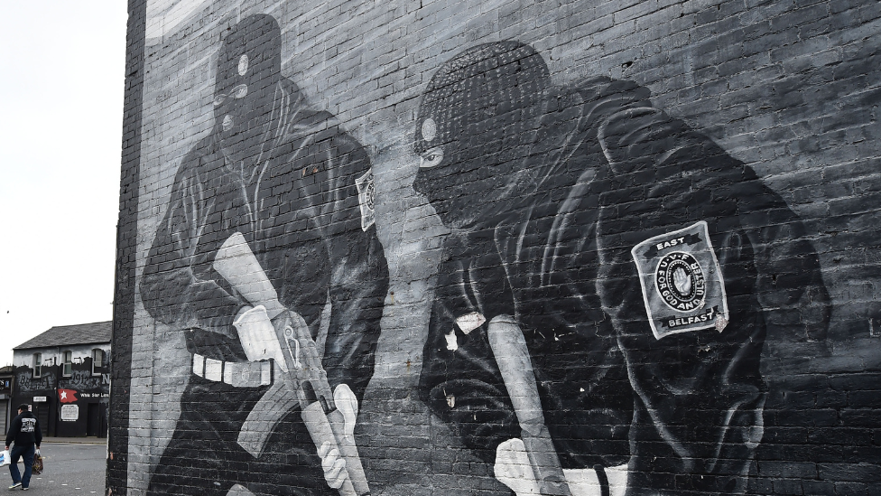 Black and white mural of two paramilitary gunmen holding guns and wearing balaclavas on a wall in east Belfast