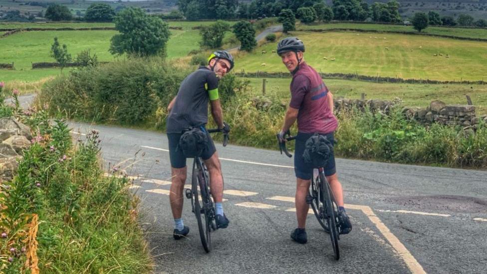 Tim and Simon on their bikes wearing cycling gear in the countryside