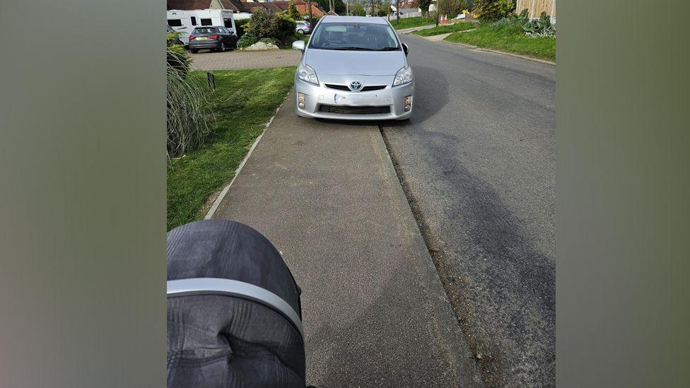 A silver car parked on the pavement