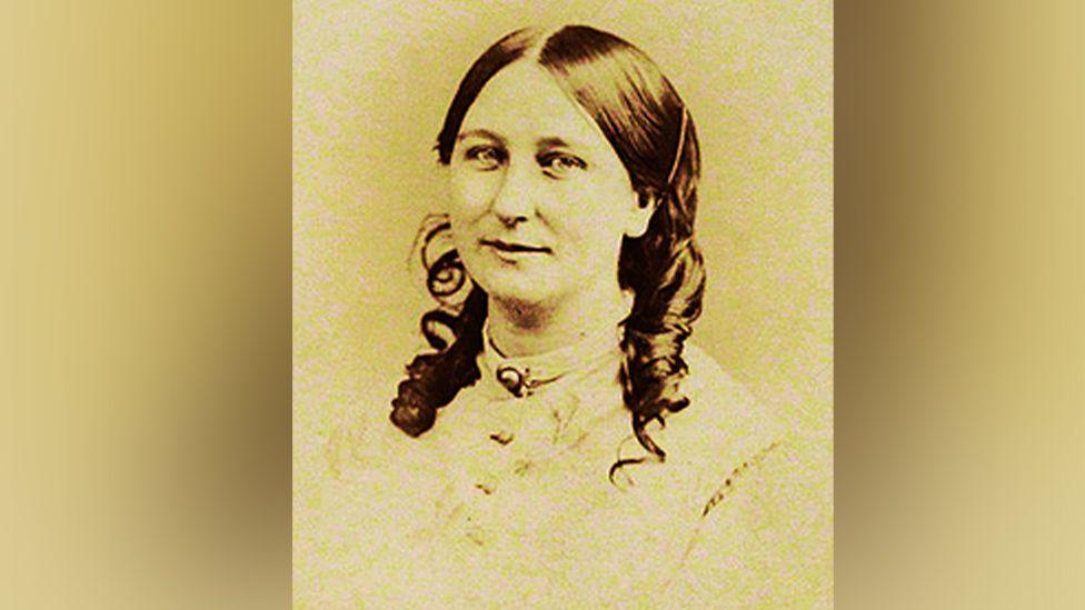 Old photo of author Charlotte Riddell in sepia tone. Her dark hair is worn in circles and she wears a coloured blouse.  