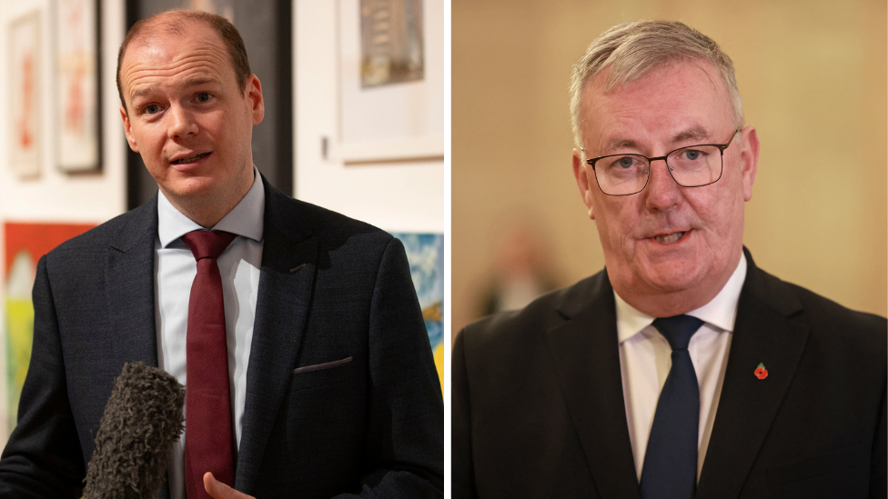 A composite image of both Communities Minister Gordon Lyons and Health Minister Mike Nesbitt. On the left, Lyons is standing in a blurred gallery talking into a microphone. He is wearing a black suit jacket, a red tie and light coloured shirt. On the right is Nesbitt talking. He is wearing a pair of square framed glasses, a dark suit jacket and tie and a white collared shirt. On his lapel is a poppy pin.