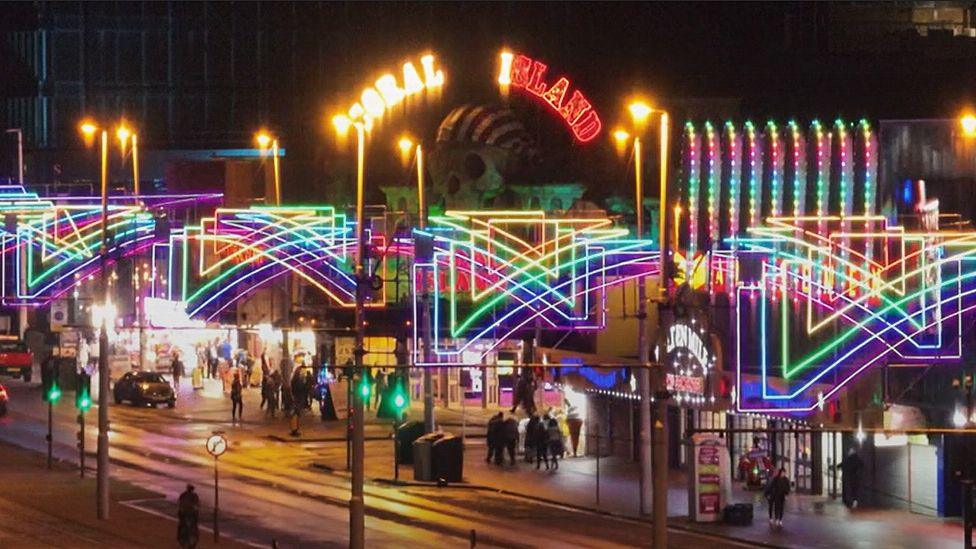 General street view of Blackpool Illuminations showing arches in rainbow neon colours