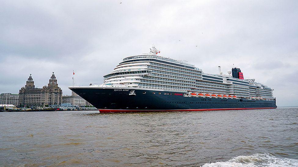Cunard's Queen Anne sailing into the Mersey ahead of a naming ceremony at Liverpool Pier Head with the Royal Liver building in the background.