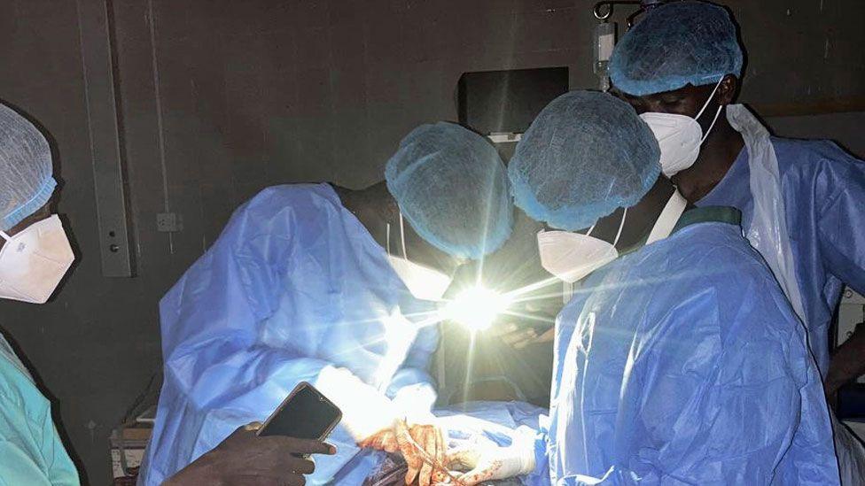 Doctors in el-Fasher's Saudi Hospital performing a caesarean using light from mobile phones