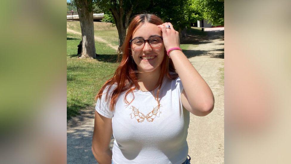 Woman wearing glasses with red hair and white t-shirt