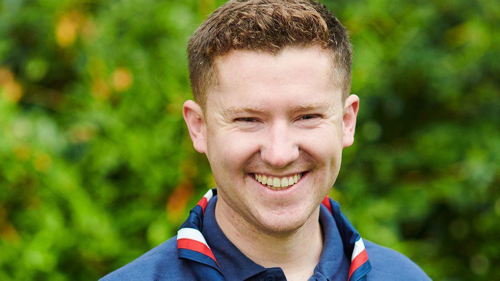 Close up of Ollie Wood, wearing a dark blue scout uniform and smiling