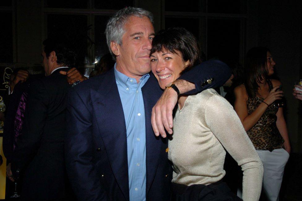 Epstein and Maxwell in an embrace in New York in 2005. He is wearing a dark blue suit and light blue shirt and is looking at the camera. Her head is pressed against his and she is smiling at the camera as his left arm is draped over her shoulder. She is wearing a cashmere top.