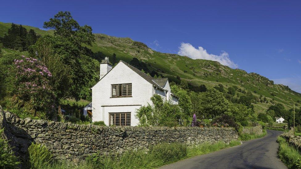 A house in the British countryside next to hills and on a country lane