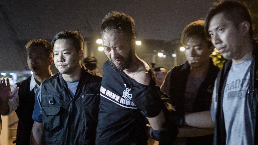 This file photo taken on October 15, 2014 shows Ken Tsang (C), a member of the Hong Kong pro-democracy political group Civic Party, being taken away by policemen outside the central government offices in Hong Kong